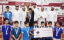 Al Adaam players pose with officials as their captain lifts the trophy. 