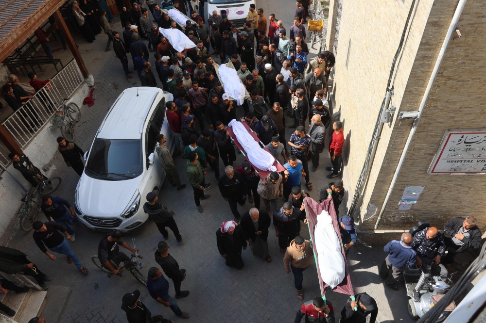 The bodies of victims killed in overnight Israeli airstrikes on the Gaza Strip are carried on stretchers at Al-Ahli Arab hospital in Gaza City ahead of their burial on March 18, 2025. (Photo by Omar AL-QATTAA / AFP)