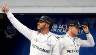 Mercedes' Lewis Hamilton of Britain celebrates pole position as Mercedes' Nico Rosberg of Germany walks by. REUTERS/Edgar Su
