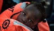 A child from African origin looks on as she is rescued from a distressed vessel by a member of Proactiva Open Arms NGO in the mediteranean sea some 20 nautical miles north of Libya on October 3, 2016. AFP / ARIS MESSINIS