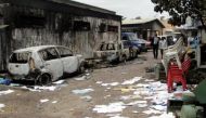 Congolese civilians walk past a house and vehicles which were burnt during anti-government protests / Reuters.