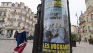 A woman walks by a poster reading 