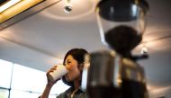 A Japanese woman drinks her beverage at a coffee shop in Tokyo. AFP / BEHROUZ MEHRI