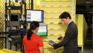 Canada's Prime Minister Justin Trudeau scans merchandise with an employee during a tour of the Amazon Fulfillment Centre in Brampton, Ontario, Canada October 20, 2016. Trudeau has set a deadline of Monday to decide whether to fly to Brussels, according to