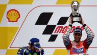 Second-placed Movistar Yamaha MotoGP's Italian rider Valentino Rossi (L) looks on as Ducati Team's Italian rider Andrea Dovizioso (R) holds up the winner's trophy as they celebrate on the podium after the 2016 Malaysian MotoGP at the Sepang International 