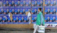 An official walks with a ballot box along election posters during the second round of parliamentary elections in Tbilisi on October 30, 2016. AFP / Vano Shlamov