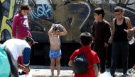 A child washes himself next to a watering hole in the refugees camp at the Greek-FYR of Macedonia border near the village of Idomeni on May 23, 2016 (AFP / SAKIS MITROLIDIS) 