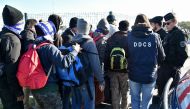 French police officers and charity workers escort young migrants to board a bus leaving for a reception centre, in Calais, on October 28, 2016 (AFP Photo/Philippe Huguen)