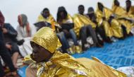 Migrants and refugees wrapped in survival foil blankets relax, aboard the Topaz Responder ship, run by Maltese NGO Moas and the Red Cross, on November 6, 2016 after a rescue operation off the Libyan coast in the Mediterranean sea. / AFP / ANDREAS SOLARO