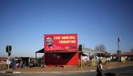 A man pushes a wheelbarrow past a billboard of the Economic Freedom Fighters which is led by Julius Malema in Soweto, South Africa, August 5, 2016.  (REUTERS / Siphiwe Sibeko) 