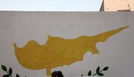 A woman walks in front of Cypriot flag painted on a wall in capital Nicosia, Cyprus November 11, 2016. REUTERS/Yiannis Kourtoglou
