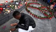 A man puts a candle near a peace symbol made with flowers on place de la Republique in Paris on November 13, 2016 as France marked the first anniversary of the Paris attacks with sombre ceremonies and painful memories for the relatives of the 130 people k