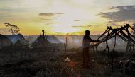 (FILES) This file photo taken on October 19, 2016 shows a man building a tent at sunset in the newly formed camp for internally displaced people in Kaga Bandoro. AFP / EDOUARD DROPSY