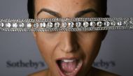 A model poses with a diamond necklace with a stunning and delicate bowknot clasp during a press preview by Sotheby's auction house on November 9, 2016 in Geneva.  AFP / FABRICE COFFRINI