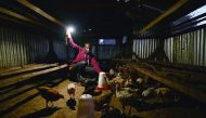 A man uses a solar-powered flashlight to tend to his chicken at kwa-Mutisya in Machakos county, some 100km southeast of Nairobi.  Consumers are opting for off-grid solar solutions to power homes and small businesses even as African governments unveil mass