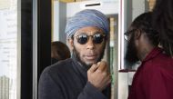 This file photo taken on March 8, 2016 shows Us hip hop artist and actor, Yasiin Bey, popularly known as Mos Def, walking out of the Bellville Magistrates Court, refusing to take off his turban as requested by security, before being due to appear for cont