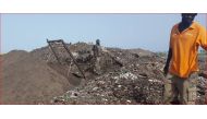 Bokk Diom manager Pape Mar Diallo stands in front of recycler Marcel Gomis in Mbeubeuss, Senegal, Oct. 4, 2016.