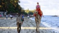 A tourist rides on a camel's back at the Jomo Kenyatta public beach in Kenya's coastal city of Mombasa, March 24, 2013. REUTERS/Joseph Okanga