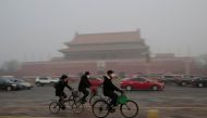 People wearing masks cycle past Tiananmen Gate during the smog after a red alert was issued for heavy air pollution in Beijing, China, December 20, 2016. REUTERS/Jason Lee
