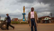 Sauveur Mulwana poses in front of one of the monuments that he created in Butembo on November 11, 2016. AFP / Eduardo Soteras 