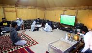 Men watch TV, play games and drink tea while gathering at a tent in a winter camp close to the border with Saudi Arabia, in al-Julaia, around 70 kilometres (45 miles) from the capital Kuwait City. AFP / Yasser Al-Zayyat