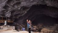 This photo taken on November 6, 2016 shows a woman holding a baby on her back in the village of Zhongdong, where a group of 18 families live inside an enormous natural cave. AFP / FRED DUFOUR
