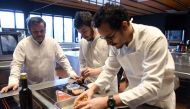 French Chef Michel Troisgros (L) cooks with his sons Cesar (R) and Leo (C), both chef, in the kitchen of their new restaurant on February 15, 2017, in Ouches, near Roanne, central France. AFP / PHILIPPE DESMAZES