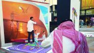 A man takes a photo of a visitor in front a 3D art work by Germany's Nikolaj Arndt during the Dubai Canvas Festival in downtown Dubai on March 1, 2017. The Dubai Canvas Festival features 25 international artists and four Emirati female artists shortlisted