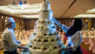 In this photograph taken on January 15, 2017, pastry chefs adorn a wedding cake before a wedding reception at the Al Meroz hotel in Bangkok. AFP / Roberto Schmidt 
