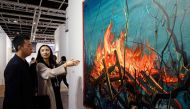 In this picture taken on March 22, 2017, Chinese investment banker Huang Xiaoshuai, 26, and his wife Wei Mengyuan chat in front of their newly acquired painting 'Fire' by Chinese artist Zeng Fangzhi, during an interview with AFP at Art Basel in Hong Kong.