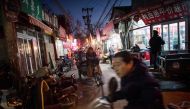 This picture taken on December 5, 2016 shows people riding in a hutong in Beijing. AFP / Fred DUFOUR