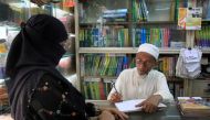 In this photograph taken on April 17, 2017, Bangladeshi novelist Kasem bin Abubakar signs an autograph for a relative at his book shop in Dhaka. AFP