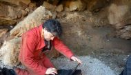 Archeologist Hipolito Collado checks his laptop prior to entering the Maltravieso Cave in the outskirts of Caceres, on February 17, 2017. AFP Photo / Handpas Project