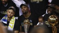 Stephen Curry #30, Kevin Durant #35 with the Bill Russell NBA Finals Most Valuable Player Award and Draymond Green #23 (holding the Larry O'Brien Championship Trophy) of the Golden State Warriors celebrate after defeating the Cleveland Cavaliers 129-120 i