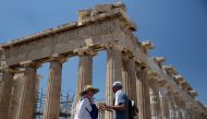 Tourists stand in front of the ancient Parthenon temple atop the Acropolis hill in Athens, Greece August 5, 2017. Reuters/Costas Baltas
