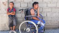 Jetullah Veliu, 16-years-old, sitting on a wheelchair along a street in the Roma neighborhood in the town of Mitrovica on July 7, 2017. AFP / Armend Nimani