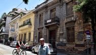 People pass a neoclassical building for sale in one of the oldest districts of Athens on July 7, 2017. AFP / Louisa Gouliamaki