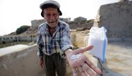 Elias al-Najar, 93, displays salt flakes in the coastal Lebanese town of Anfeh north of the capital Beirut on July 21, 2017.  AFP / Ibrahim Chalhoub