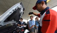 This picture taken on July 23, 2017 shows an instructor (R) using a dipstick to check engine oil levels during a lesson on car maintenance at a driving school for senior citizens, managed by the Japan Automobile Federation (JAF), in Kanuma, Tochigi prefec