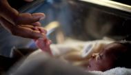 FILE PHOTO: A man touches his newborn baby born three days earlier at the Israeli hospital in Port-au-Prince, January 20, 2010.  Reuters / Carlos Garcia Rawlins