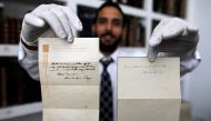 A picture taken on October 19, 2017, shows Gal Winner, owner and manager of the Winner's auction house in Jerusalem, displays one of two notes written by Albert Einstein, in 1922, on hotel stationary from the Imperial Hotel in Tokyo Japan. AFP / Menahem K