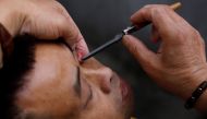 A file photo of Xiong Gaowu, a 62-year old street barber cleans his customer eye using the straight razor in Chengdu, Sichuan province, China. REUTERS/Tyrone Siu