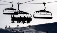 (FILES) This file photo taken on January 2, 2017 shows skiers sitting in a ski lift as others ski down a slope in the Swiss Alps resort of Les Crosets. AFP / FABRICE COFFRINI