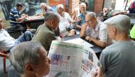 A man reads a newspaper as others play checkers in Singapore January 16, 2018. Reuters/Calvin Wong