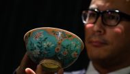 Nicolas Chow, deputy chairman for Sotheby's Asia, holds an extremely rare Qing Dynasty bowl -- one of only three known to exist -- during a media preview at auction house Sotheby's in Hong Kong on March 1, 2018, before its upcoming sale on April 3. AFP / 