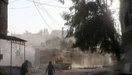 Syrians walk in the street covered in dust following reported government bombardments on the rebel-held town of Hamouria, in the besieged Eastern Ghouta region on the outskirts of the capital Damascus on March 5, 2018. / AFP / ABDULMONAM EASSA
