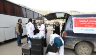 Aid workers wait for busses carrying rebel fighters and their families to arrive in the Qalaat al-Madiq village in the province of Hama, on March 13, 2018, after being evacuated from the Qadam neighbourhood on the outskirts of Damascus under a deal agreed