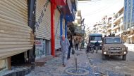 A picture taken on March 19, 2018, shows a man walking near broken glass next to Turkish-backed Syrian fighters in the seized Kurdish-majority city of Afrin.  AFP 
