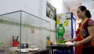 In this photograph taken on March 20, 2018, a waitress carries dishes to customers next to the glass-encased table where former US President Barack Obama sat at for a meal with chef Anthony Bourdain at Bun Cha Huong Lien restaurant, now dubbed 