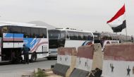 Syrian government buses gather to evacuate civilians and rebel fighters from the town of Douma on the government side of the Wafideen checkpoint on the outskirts of Damascus neighbouring the rebel-held Eastern Ghouta region, on April 3, 2018.   AFP / Loua